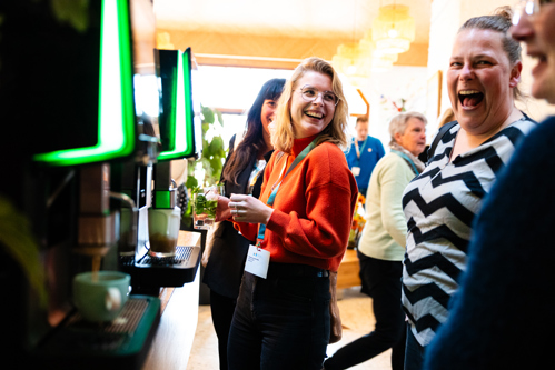 Lachende mensen bij het koffie apparaat op een congres van Medilex Onderwijs